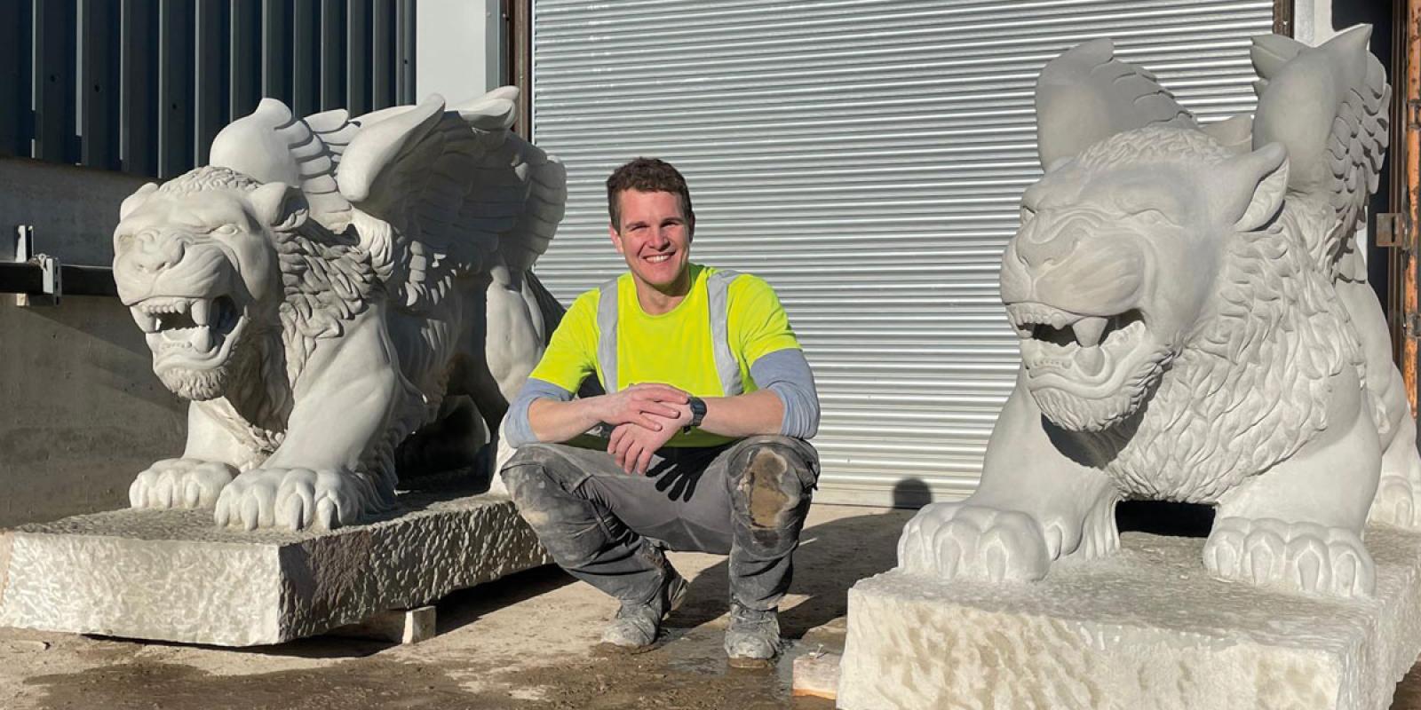 Ryan outside his workshop at Traditional Stone with the two completed griffins